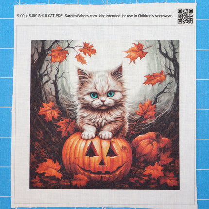 Fabric panel with a kitten on a pumpkin and autumn leaves design, on a blue tiled background.